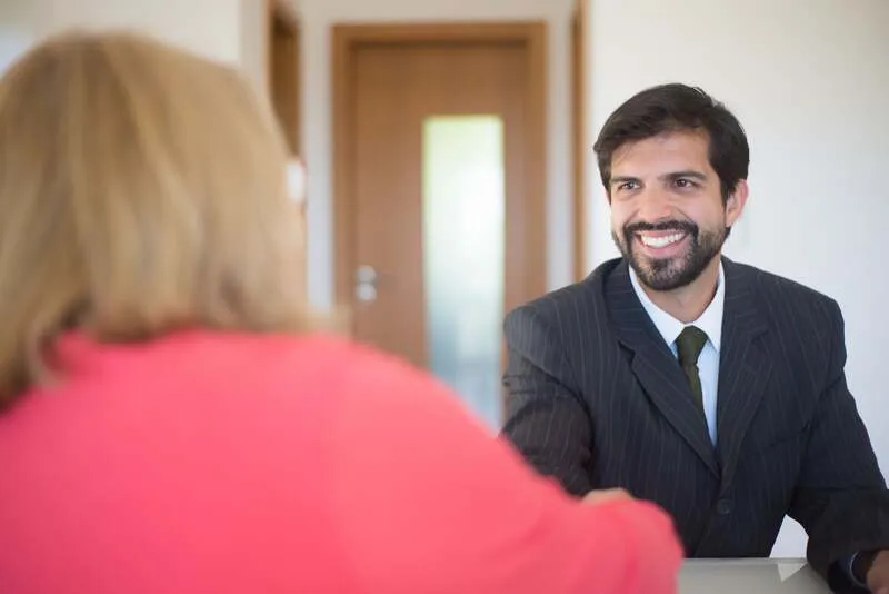 Deux professionnels discutent un devis autour d'une table, documents et calculatrice visibles